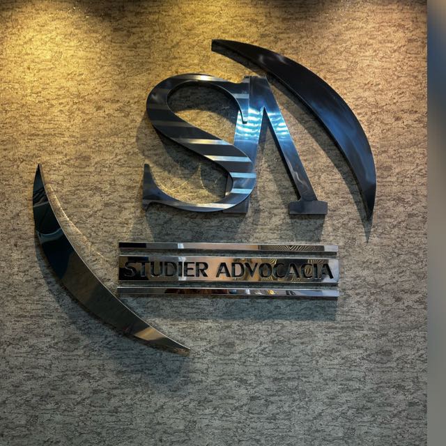 Logotipo metálico da Studier Advocacia na parede do escritório